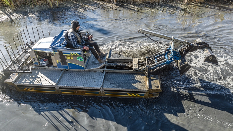 Person driving a Truxor machine in a pond with a claw attachment